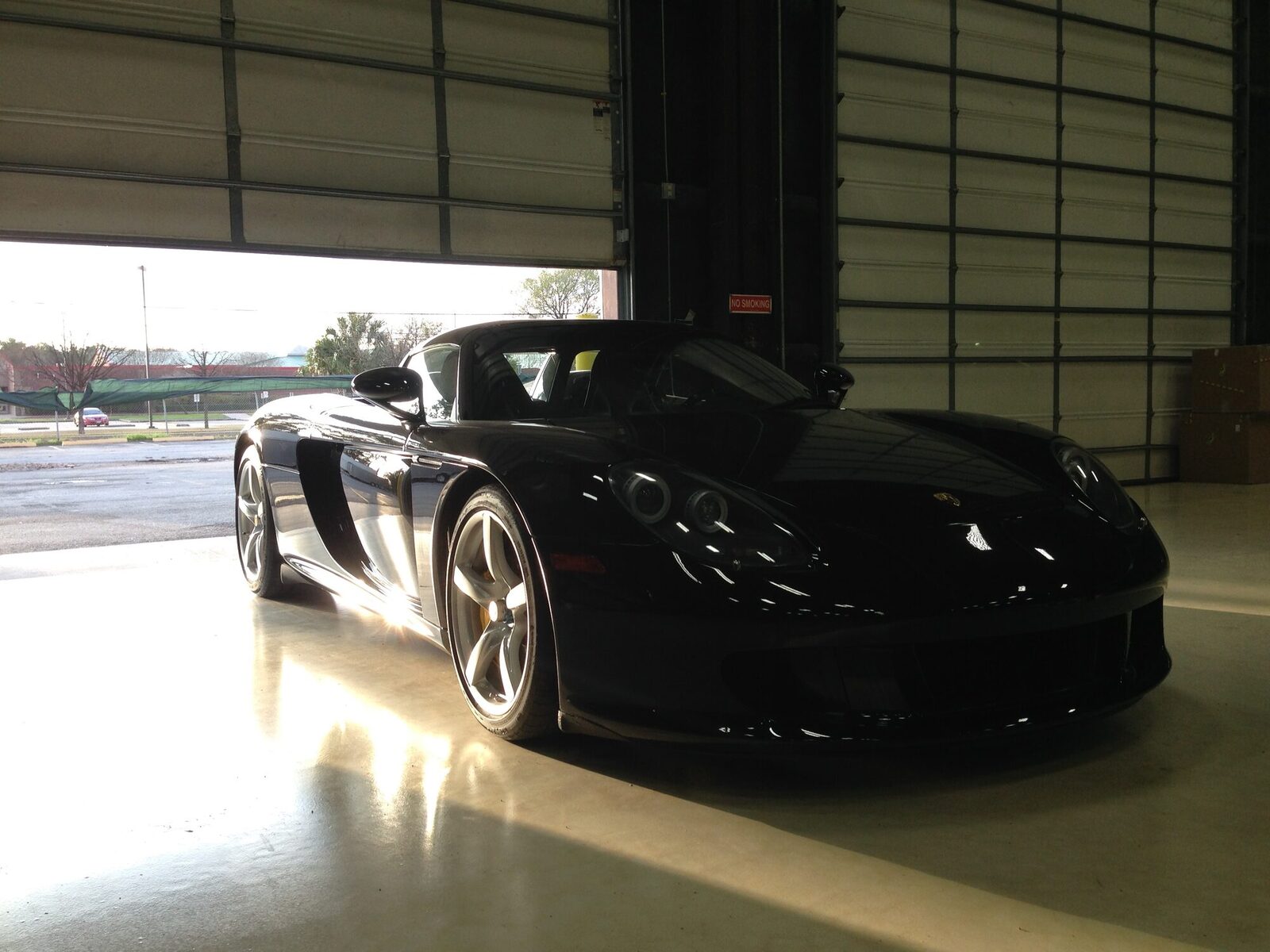 A black Porsche Carrera GT parked at the open bay door