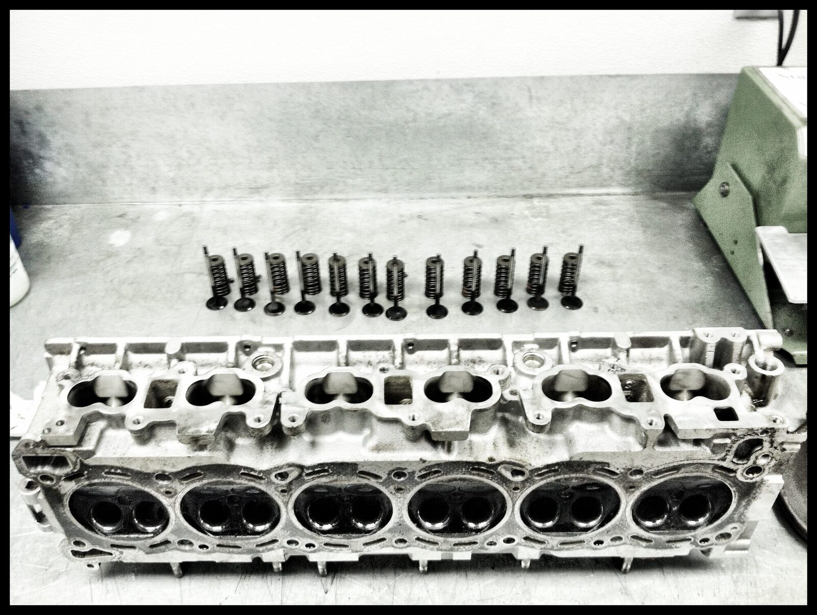 A cylinder head on the bench with its valves laid out in order