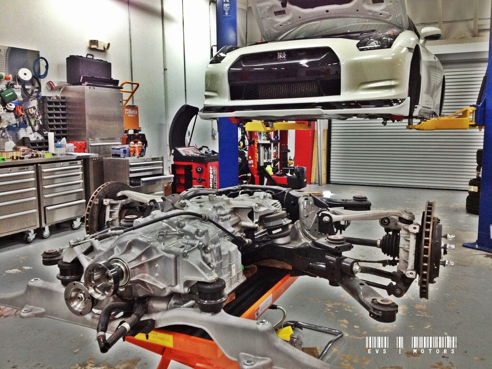 A Nissan GT-R on a lift with its engine and subframe removed beneath it