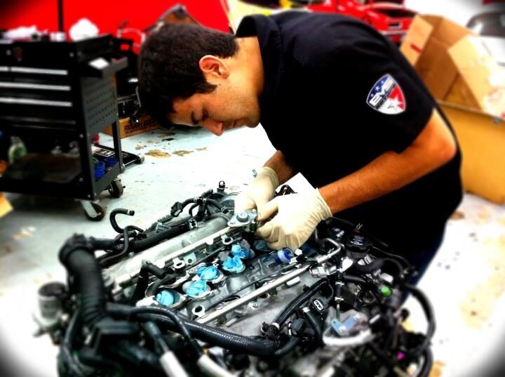 John fitting a fuel rail and injectors onto an engine in the shop