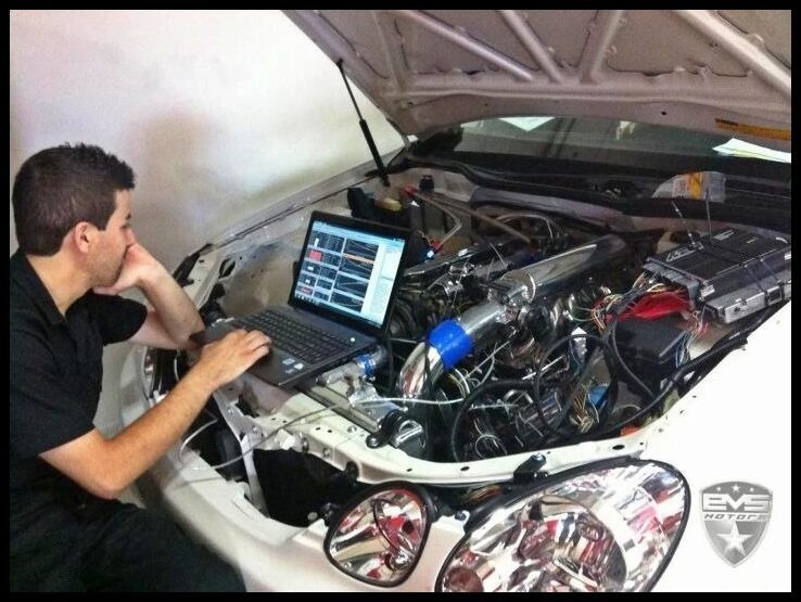 John tuning from a laptop on the fender of a car with its engine bay open
