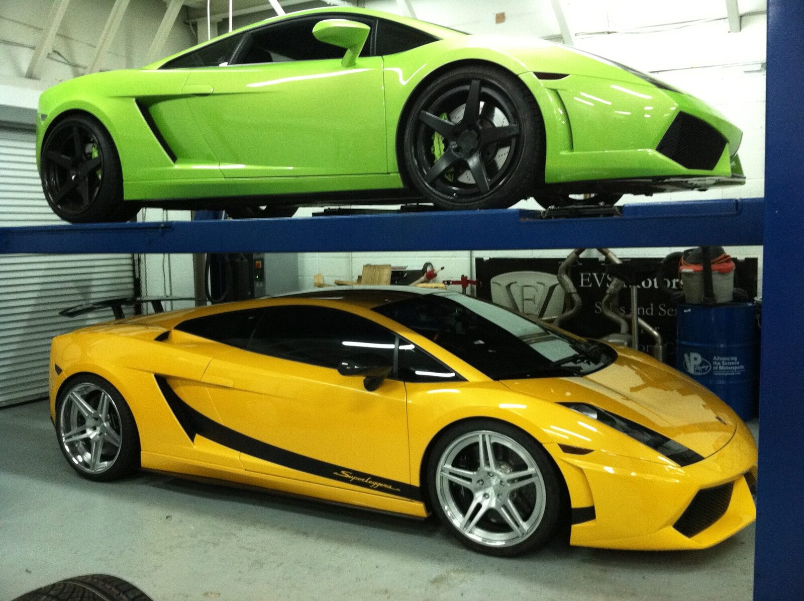 A green Lamborghini Gallardo on a lift above a yellow Gallardo